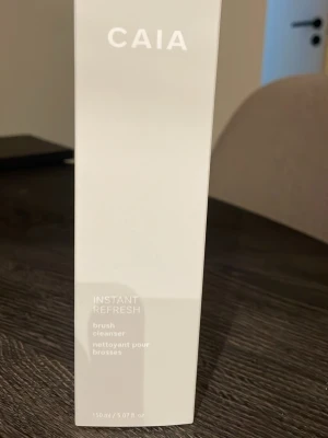 CAIA Instant Refresh brush cleanser - Säljer en helt ny oanvänd CAIA Instant Refresh brush cleanser, 150 ml. Kommer i en stilren, genomskinlig flaska med vit kork och vit text. Perfekt för att snabbt rengöra dina sminkborstar och hålla dem fräscha mellan användningarna.