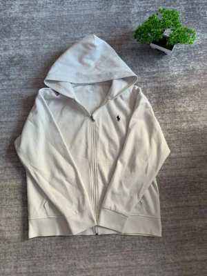 Ralph Lauren zip up - Authentic Ralph Lauren zip-up sweatshirt in classic white 🤍. Made from soft, high-quality cotton for a comfortable fit ✨. Features the iconic Ralph Lauren logo on the chest 🐎. Gently used, in good condition 👍. Price is negotiable 💸.  Size: M Condition: Good ✅