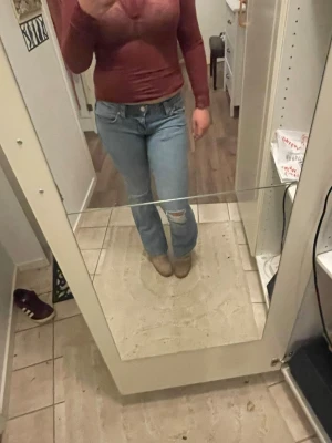 Ljusblå bootcut jeans från Gina tricot - Säljer ett par ljusblå jeans med bootcut passform och klassisk femficksdesign. Jeansen har en liten sliten detalj vid knät och är tillverkade i mjukt denimtyg. Perfekt för dig som gillar en avslappnad och snygg stil.