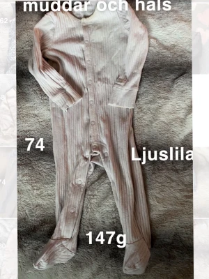Ljuslila randig babypyjamas  - Supersöt ljuslila babypyjamas med tunna ränder och knappar hela vägen framtill. Pyjamasen har långa ärmar och fötter, perfekt för mysiga dagar. Mjuk och skön känsla mot huden.🌸 Fläckar. Storlek 74