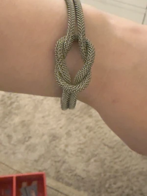 Ingen väst på bilderna - Bilderna visar ett armband i metall med knutdetalj, inte en väst.