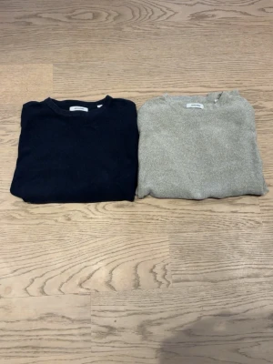 Grå & mörkblå stickad tröja från Jack & Jones,  man får båda.  - Säljer en grå och en mörkblå  stickad tröja från Jack & Jones med rund hals och långärmad passform. Tröjan har en enkel och stilren design, perfekt för dig som gillar en clean look. Materialet är mjukt och känns skönt mot huden. Frakt ingår ej. Man får båda tröjorna med på köpet. Hör av dig ifall du vill se mer bilder. 