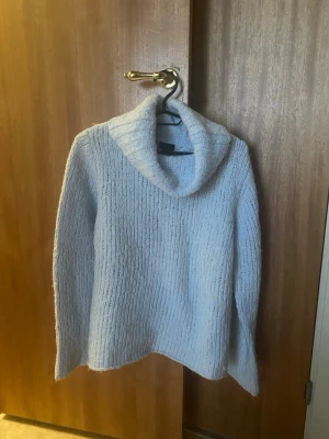 Ljusblå stickad polotröja Lindex M - Mysig ljusblå stickad polotröja från Lindex i storlek M (40/42). Tröjan har en bred polokrage och är ribbstickad med lång ärm. Perfekt för kyliga dagar och enkel att styla med jeans eller kjol.