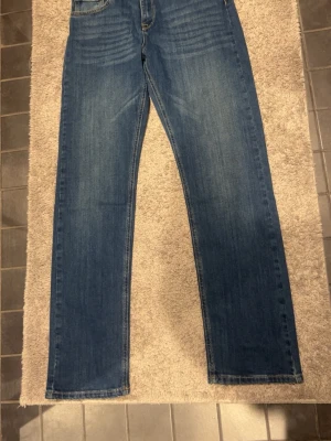 Blå Replay jeans straight fit - Säljer ett par klassiska blå jeans från Replay med raka ben och snygga slitningar framtill. Jeansen har fem fickor och Replay-lapp bak i midjan. Perfekta till sneakers eller boots och passar till många olika stilar. Helt nya, aldrig använda.