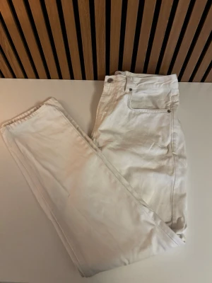 Vita bagy jeans - Säljer ett par klassiska vita  jeans. Jeansen har metallnitar vid fickorna och är tillverkade i bomull. Perfekta för dig som vill ha en clean och tidlös look. Köpte jeansen för 300 kronor på lager 157 men har aldrig använt dem.