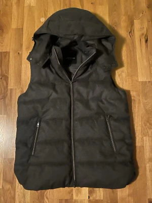 Mörkgrå dunväst från Lawrence Grey - Snygg mörkgrå dunväst från Lawrence Grey med avtagbar huva och två dragkedjeförsedda fickor. Västen har quiltad design och hel dragkedja framtill. Perfekt för lager-på-lager och enkel att matcha med olika outfits perfekt till vinter den är svår o hitta och är väldigt fin. Den är även varm den är k storlek s men oasssr bättre som m