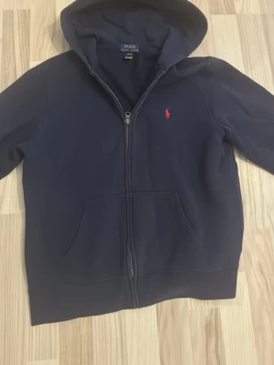 Ralph lauren hoodie - En mörkblå tröja från polo ralph lauren med en dragkedja. Tröjan är i extremt fint skick och är knappast använd. 