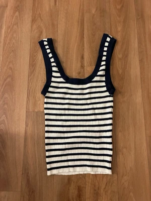 Randig ribbad linnetopp H&M Divided - Säljer en ribbad linnetopp från H&M Divided i storlek XS. Toppen är vit med mörkblå ränder och har breda axelband. Perfekt till sommaren och enkel att matcha med jeans eller kjol.