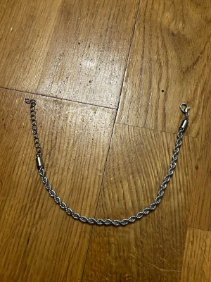 Snygg silverfärgad kedja - En stilren och enkel silverfärgad kedja med tvinnad design och karbinhake. Passar perfekt som accessoar till byxor eller väska för en cool look. Justerbar längd tack vare extra länkar. Metallfinish som ger en modern vibe.