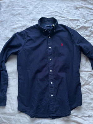 Mörkblå Ralph Lauren skjorta - Snygg Ralph Lauren skjorta, som inte kommer till användning så mycket. Skjortan har inga defekter och kom gärna med prisförslag för priset är inte hugget i sten :)