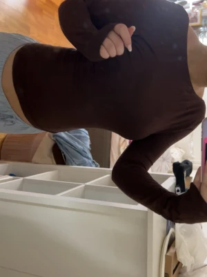 Brun långärmad topp med öppen rygg - Säljer en enkel och stilren brun långärmad topp i mjukt bomullsmaterial. Toppen har en  öppen rygg, rund halsringning och en tight passform som framhäver figuren. 