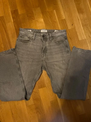 Grå jeans från Jack & Jones, 29/32 - Snygga grå jeans från Jack & Jones i klassisk femficksmodell. Jeansen har rak passform, knappgylf och coolt tvättad look. Perfekt för dig som gillar en enkel och stilren vibe. Storlek 29/32. Öppen för prisförslag.