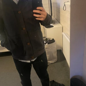 Mörkblå overshirt från J.Lindeberg - Snygg mörkblå overshirt från J.Lindeberg med klassisk krage och stora framfickor. Jackan har knäppning med bruna knappar och är tillverkad i bomull. Overshirten är i storlek M, för stor för mig som är storlek s vilket syns i bilderna. Inga defekter. Borde kanske strykt den…