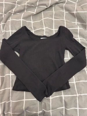 Svart långärmad topp - Säljer en svart ribbad långärmad topp från H&M med rundad halsringning och croppad passform. Toppen är i mjuk bomull och har diskret dekorativ kant vid halsen. Perfekt att styla med jeans eller kjol för en chill look. Säljer då den inte används, skulle säga att den är som i nyskick då jag aldrig andvänt den! Skriv gärna över funderingar. 💞