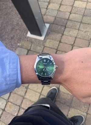 Grön och silver klocka från Doventi  - Snygg klocka från Doventi med grön urtavla och silverfärgat armband i metall. Urtavlan har datumvisning och stilrena markeringar. Perfekt accessoar för dig som vill sticka ut med en modern och fräsch look. Skickas med box och går att ändra storlek.