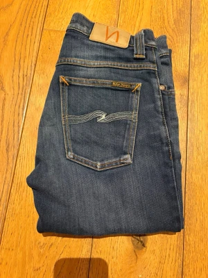 Nudie Jeans Grim Tim - Säljer ett par riktigt feta Nudie jeans av modellen Grim Tim som är i mycket bra skick. Sjukt bra passform och de är W28 som står i byxorna. De är L32 i längd. Riktigt feta och mycket fräscha. Hör av er vid frågor.