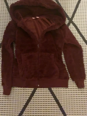 Hunkemöller  - Vinröd fluffig jacka. Är i storlek M men Jag är en Xs och den passar perfekt för mig! Super mysig att ha på sig och man kan ha hoddie under❤️