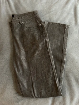 Grå skimriga jeans med ormskinnsmönster från Laura Kent - Snygga grå skimriga jeans från Laura Kent med diskret ormskinnmönster i storlek 38. 