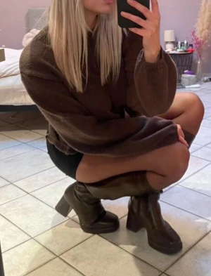 Brun stickad tröja med öppen rygg - Säljer en brun stickad tröja med oversized passform och långa ärmar. Tröjan har en cool öppen rygg med knytband som ger en unik look. Perfekt för dig som vill ha något annorlunda och trendigt i garderoben.