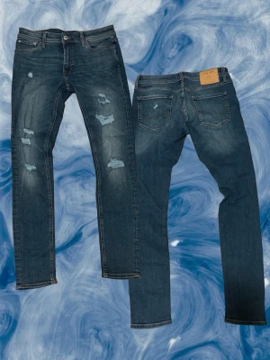 Jack & Jones Skinny Fit Liam Jeans - Mörkblå skinny jeans från Jack & Jones, modell skinny Liam. Snygga slitningar framtill för en trendig look. Jeansen är bra skick 9/10.