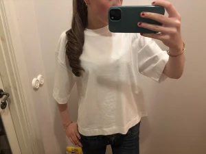 Vit oversized t-shirt i bomull - Säljer en oanvänd vit oversized t-shirt med korta ärmar och rund hals. T-shirten är tillverkad i mjuk bomull och har en avslappnad passform som ger en skön och trendig look. Perfekt att matcha med jeans eller shorts.