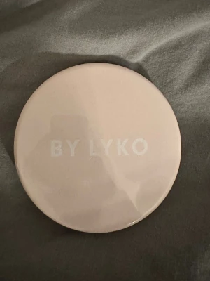 Rund sminkspegel med LED från By Lyko - Säljer en rund, ljusrosa sminkspegel från By Lyko med inbyggd LED-list. Bra att ha med i väskan för att fixa sminket när som.