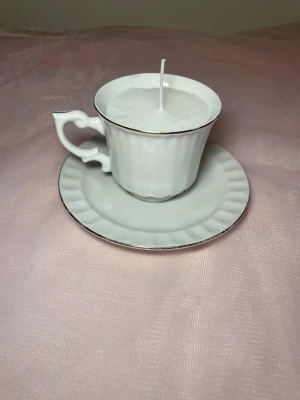 Doftljus i tekopp i en vit färg nr 1  - Det här ljuset är gjort av återanvändbara material. Tekoppen är köpt secondhand och stearinet är från kyrkor som tänkte slänga det. Det här ljuset har en svag doft utav vanilj, så känsliga även kan använda det. Det finns fler ljus i samma design på hemsidan ifall man vill köpa sets. 