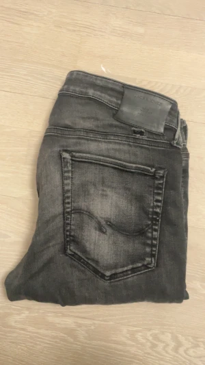 Svarta skinny jeans från Jack & Jones - Snygga svarta jeans från Jack & Jones med skinny passform och klassisk femficksdesign. Jeansen har en tvättad look och detaljerade sömmar. Perfekt för dig som gillar en smal siluett och vill ha ett par jeans som sticker ut. Jeansen har ett par slitningar. Det är modellen Glenn.