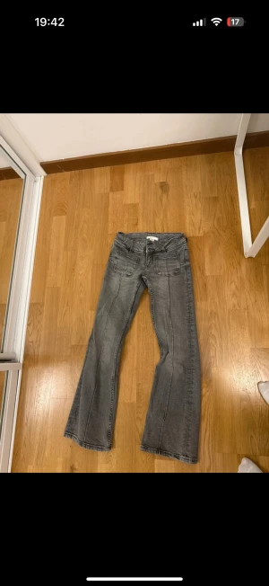 Grå bootcut jeans från Gina Tricot - Snygga grå jeans från Gina Tricot med bootcut-ben och klassiska fickor både fram och bak. Jeansen har en cool tvättad look och är tillverkade i mjukt denimtyg. 