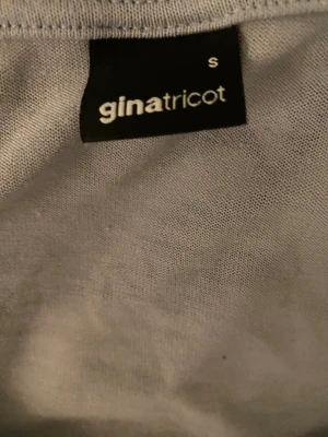 Ljusblå omlottopp från Gina Tricot - Trendig ljusblå omlottopp från Gina Tricot med lång ärm och djup v-ringning. Toppen har knyt framtill som ger en snygg och croppad look. Perfekt att styla med jeans eller kjol för en cool outfit.