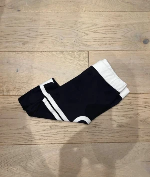 Svarta leggings från Aim'n XS - Snygga svarta leggings från Aim'n med vit bred midja och coolt vitt tryck längs benet. Tillverkade i stretchigt material med 73% polyester och 27% spandex för skön passform. Perfekta för träning eller chill dagar.