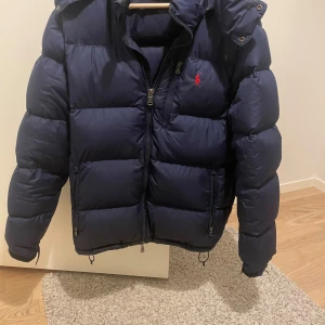Mörkblå dunjacka från Polo Ralph Lauren - Mörkblå ralph lauren jacka i väldigt bra skick, storleken är medium men passar mig som använder small bra också☺️nypris är runt 5000. Mitt pris: 2499. Pris är diskuterbart.