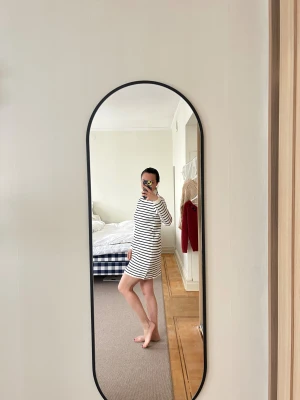 Randig vit och svart klänning från MNG - Säljer en kort, vit klänning med svarta horisontella ränder från MNG. Klänningen har lång ärm, rak passform och en hög, rundad hals. Materialet är mjukt och stickat, vilket gör den skön att bära. Perfekt för dig som gillar enkel och stilren design.