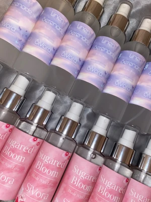 SiVora Body Mist Duo - Två olika body mists från SiVora: Linen Serenade med drömmigt lila etikett och Sugared Bloom med rosa blommig design. Båda är märkta 'Made With Love'. Perfekt för dig som vill ha en fräsch och söt touch i din vardag.