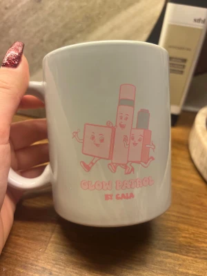 Glow Patrol by CAIA Mugg - Söt vit mugg med rosa tryck 'Glow Patrol by CAIA'. Motiv med glada sminkfigurer. Muggen är helt ny, finns inte att köpa.