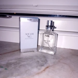 Aqua di NG Eau de Toilette - Fräsch Eau de Toilette från NG, levereras med originalförpackning. Perfekt för dig som vill ha en stilren och modern doft i din samling. Volym och ingredienser framgår ej på bilderna.