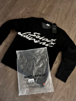 Saint Laurent tröja svart - Helt ny Saint Laurent tröja i svart. Jätte varm och fin tröja som passar perfekt till denna väder nu❄️svart tröja med vit skriver saint laurent. Storlek S