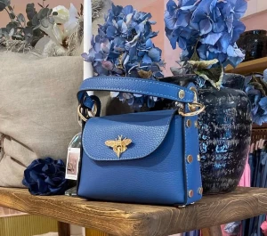 Blå axelväska med gulddetaljer - Snygg blå axelväska i skinn med guldfärgad kedja och dekorativt bi på locket. Väskan har både handtag och axelrem, samt nitar på sidorna. Perfekt storlek för det viktigaste och ger en trendig vibe till din outfit.