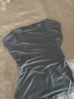 Ljusblå topp från Lager157, storlek S - Säljer en ljusblå topp från 15:O i storlek S. Toppen har en enkel och clean design med korta ärmar och rund hals. Materialet känns mjukt och lätt, perfekt för dig som gillar minimalistisk stil. Snygg att matcha med jeans eller kjol.