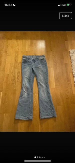 Blå bootcut jeans från Replay - Snygga ljusblå jeans från Replay med bootcut passform och klassisk femficksdesign. Jeansen har broderade detaljer på bakfickorna och är tillverkade i mjukt denim med dragkedja och knapp framtill. Perfekt för dig som gillar retrovibbar och bekväm stil.