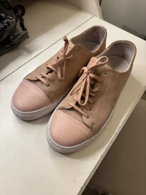 Rosa sneakers från Axel Arigato - Säljer ett par snygga sneakers från Axel Arigato i storlek 41 då jag använt dom en gång. Köpte dom second hand med prislappen kvar för 500. Dom är fortfarande i bra skick men lite grå defekter förekommer. 