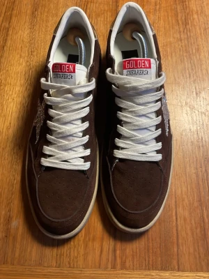 Golden goose ballstar - Ett par helt nya och unika Golden goose ballstar i färgen brun med silverglittrande och guldiga detaljer. Skorna är helt nya utan några defekter eller användning. Jag har tyvärr bara skorna. Skorna är perfekt för dig som gillar en unik men snygg stil. Priset är ej hugget i sten.