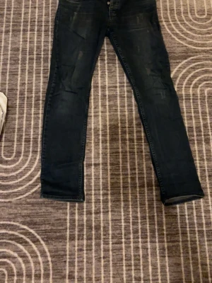 Mörkblå Denim Miganon slim fit jeans - Slim fit jeans från Denim Miganon i mörkblå tvätt med snygga slitningar och klassiska fem fickor. Jeansen har en smal passform och är tillverkade i jeansmaterial med detaljerade sömmar och läderpatch bak i midjan.