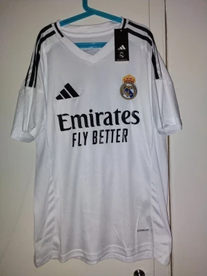 Real madrid tröjan med Valverde på ryggen🤩  - (Tröjan är nu med prislapp!) Bilderna visar en vit Real Madrid fotbollströja från Adidas med svarta detaljer och Valverde 8 på ryggen. Ingen sko finns på bilderna.