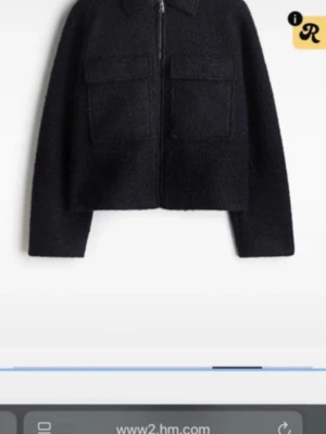 Svart teddyjacka från H&M - Svart teddyjacka från H&M med croppad passform och två stora fickor framtill. Jackan har dragkedja och klassisk krage, perfekt för dig som gillar en chill och trendig look. Materialet är mjukt och fluffigt, vilket gör den extra skön att bära.