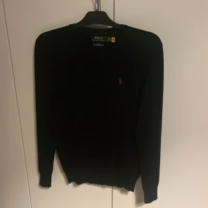 Svart merinoullströja Polo Ralph Lauren - Pris går att diskuteras vid snabb affär!    Svart långärmad tröja från Polo Ralph Lauren i slim fit-modell. Tillverkad i tvättbar merinoull och har en liten broderad logga på bröstet. Perfekt för dig som gillar klassisk och stilren look.