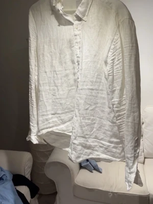 Vit linneskjorta från Bläck - Säljer en stilren vit skjorta från Bläck i linnematerial. Skjortan har klassisk krage, långa ärmar och knappar framtill. Passformen är slim och tyget är lätt och luftigt, perfekt för varmare dagar. Enkel och fräsch look som funkar till många outfits.