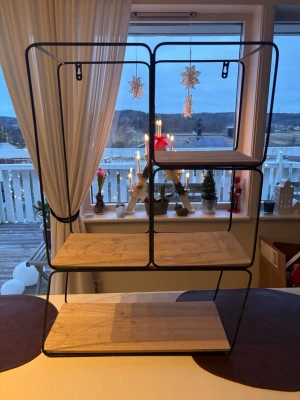 Hylla - hylla med svart metallram och träplan.