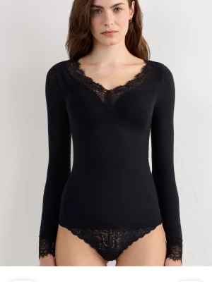 Ultralight lång blus i modalkashmir och spets - Supersnygg svart långärmad blus med v-ringning och spetsdetaljer både vid halsringningen och vid ärmsluten. Toppens material är Kashmir och följsamt, perfekt att styla med jeans eller kjol för en chic look. Helt nytt skick med prislapp kvar