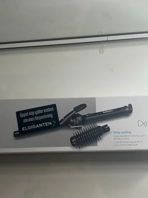 Babyliss svart locktång keramisk - Babyliss locktång med extra lång keramisk cylinder på 16mm för enkel styling. Svart design med avtagbar borste och roterbar sladd på 1,8 meter. Max temperatur 185°C. Perfekt för att skapa snygga lockar och volym.